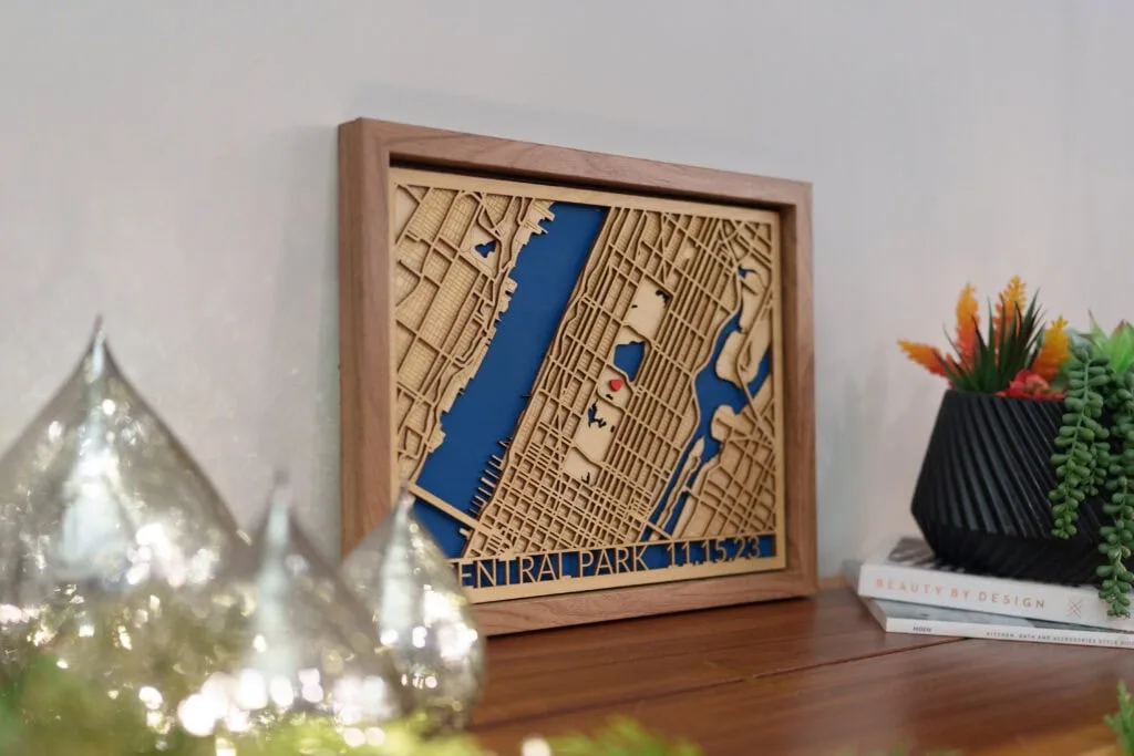 Laser cut map of Central Park with blue water features and detailed street layout.